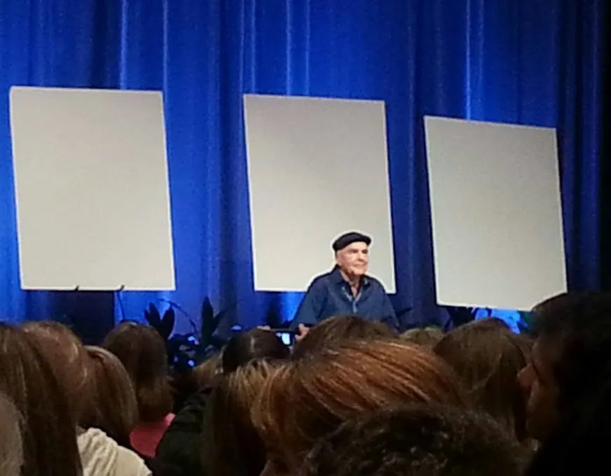 Dr. Wayne W. Dyer seated on stage before an audience in Portland, Oregon